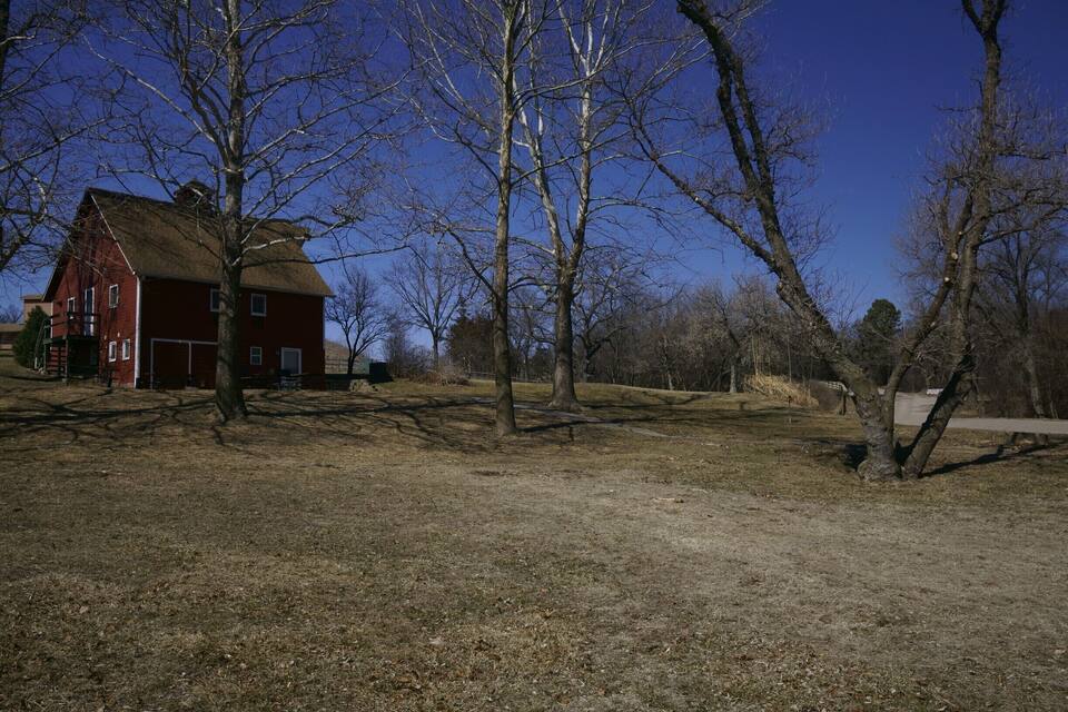 A red barn, leafless trees, and a clear blue sky.
