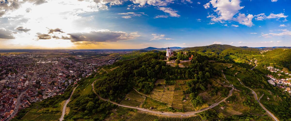 A panoramic view of a town surrounded by lush green hills and a prominent church on a hilltop.