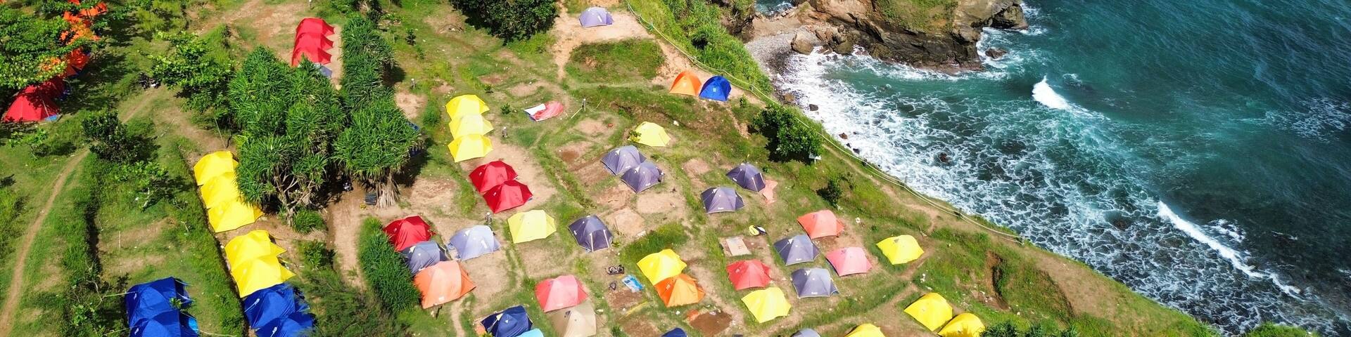 Aerial drone view of coastline with hills and trees, as well as view of coral cliffs and sea with waves from the ocean in Menganti Beach Kebumen Central Java Indonesia