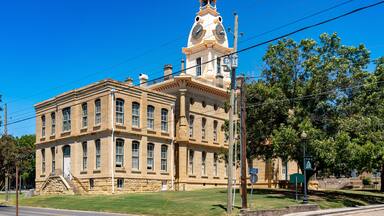 A historic building with a clock tower, large windows, and a well-maintained lawn.