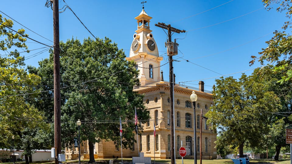 A historic building with a clock tower, surrounded by trees and utility poles.