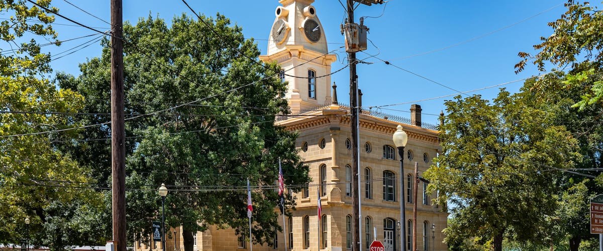 A historic building with a clock tower, surrounded by trees and utility poles.
