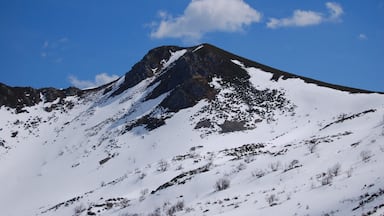 Ein mit Schnee bedeckter Berg mit felsigen Gipfeln und blauem Himmel.