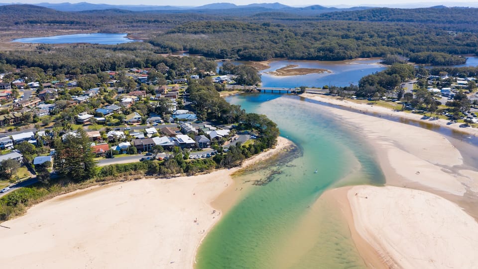 A coastal town with a river, beach, and bridge.