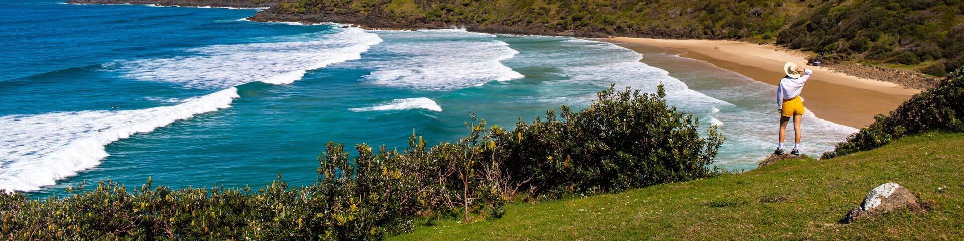 Girl in a hat sits and admires stunning hidden O'connors beach (cove) in Hat Head National Park, Korogoro walking track; NSW, Australia. Australian beautiful bays