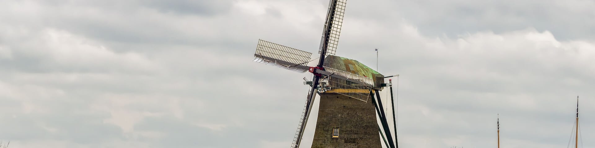 View of the historic thatched Veendermolen with miller's cottage on the bosom of the Weide Aa near the Dutch village of Roelofarendsveen against the background of a winter cloudy sky