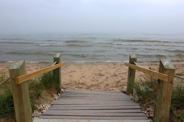 Beautiful midwest nature background. Landscape with wooden boardwalk to the beach through sand dunes and mist over the lake Michigan at Kohler-Andrae State Park, Sheboygan area, Wisconsin, USA.