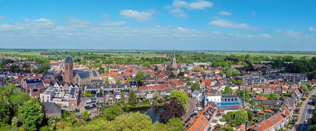 A town with a prominent church, a river, and surrounding green fields.