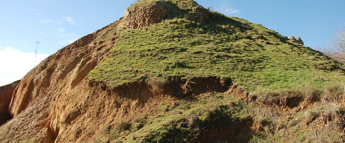 A rugged hill with a rocky peak and sparse vegetation.