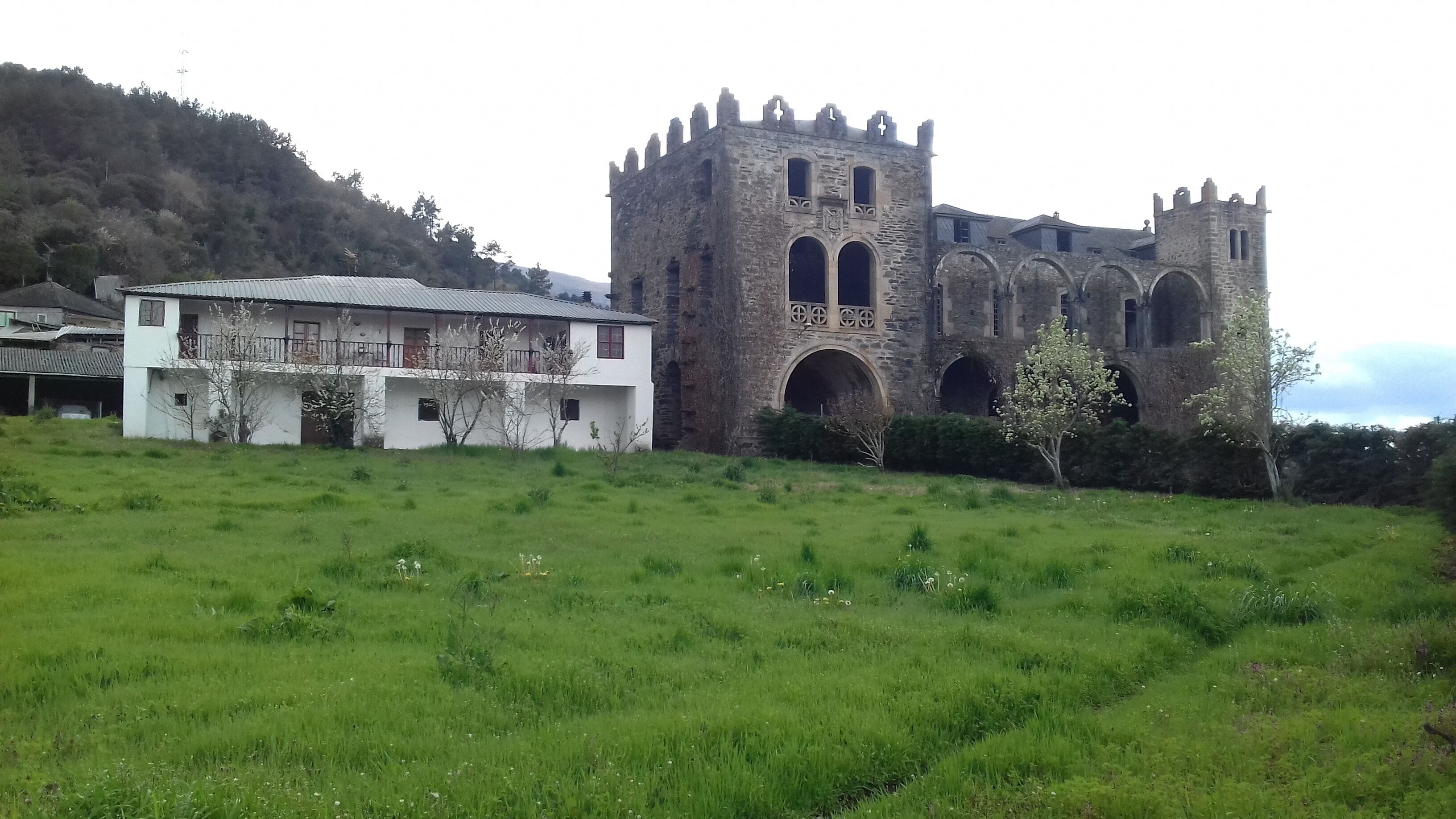 A historic stone tower with arched windows and a white building with a metal roof in the foreground.