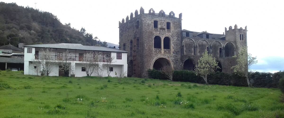 A historic stone tower with arched windows and a white building with a metal roof in the foreground.