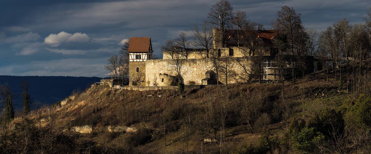 A historic stone castle on a hill with a clear sky.