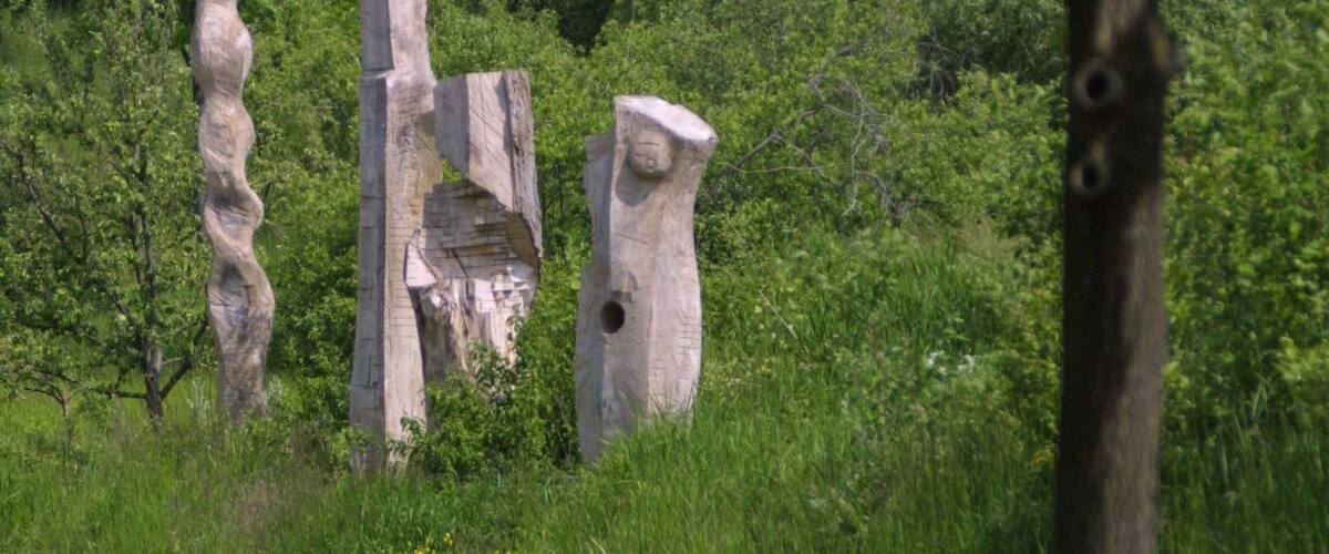 A road with three large stone sculptures in a grassy area.