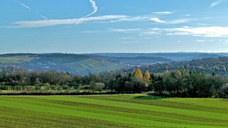 A rural landscape with green fields, a distant town, and rolling hills.