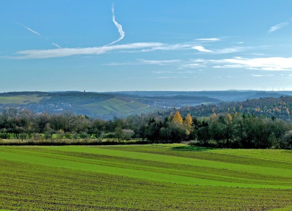A rural landscape with green fields, a distant town, and rolling hills.