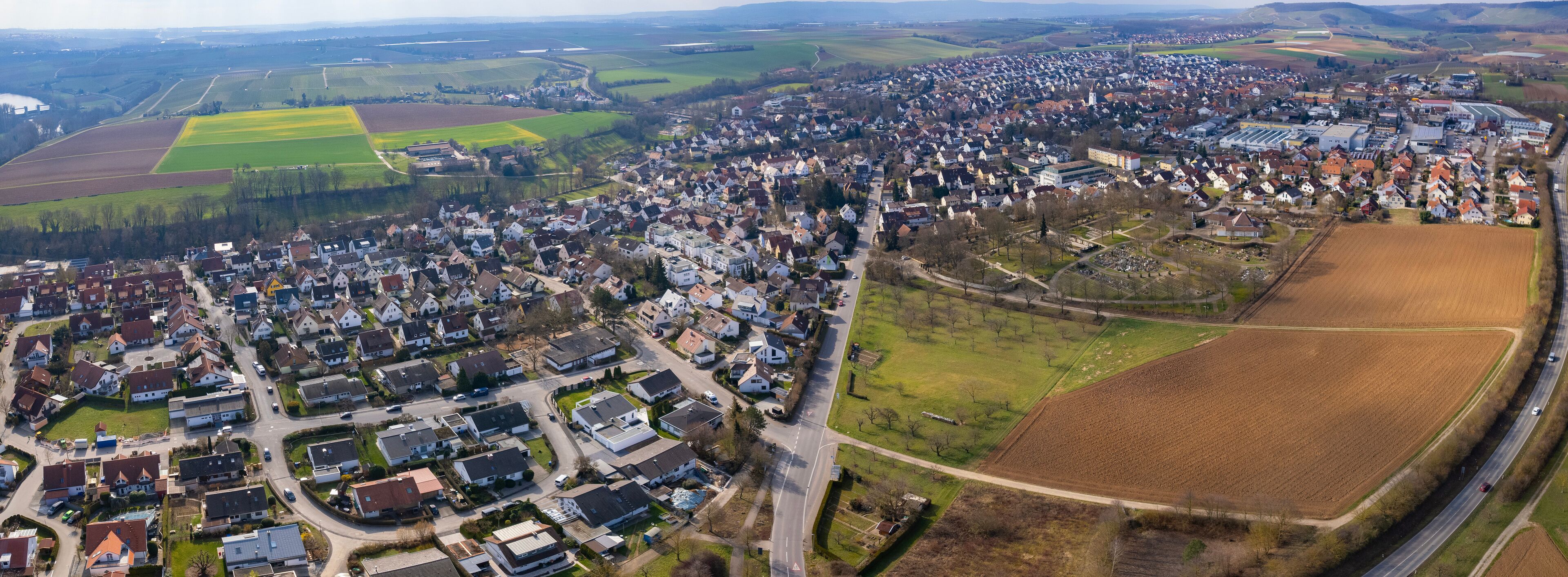 An aerial view of a town with residential areas, agricultural fields, and a highway.