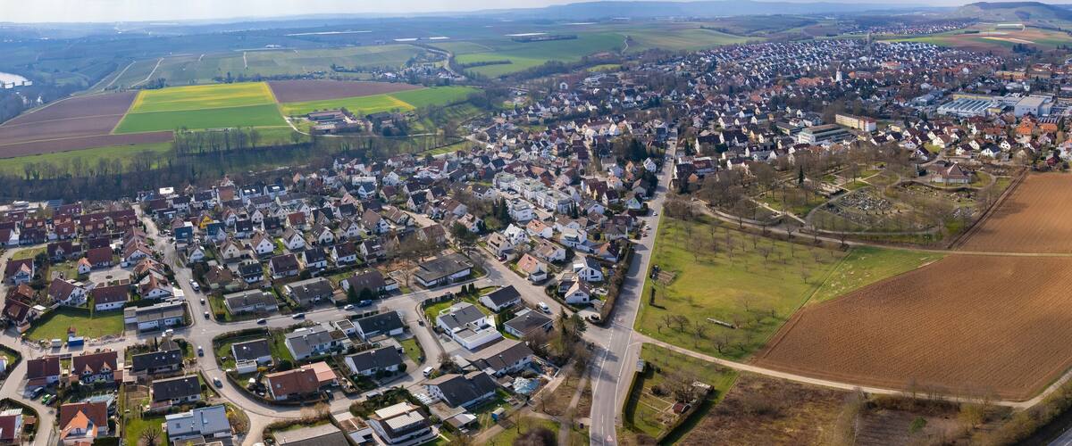 An aerial view of a town with residential areas, agricultural fields, and a highway.