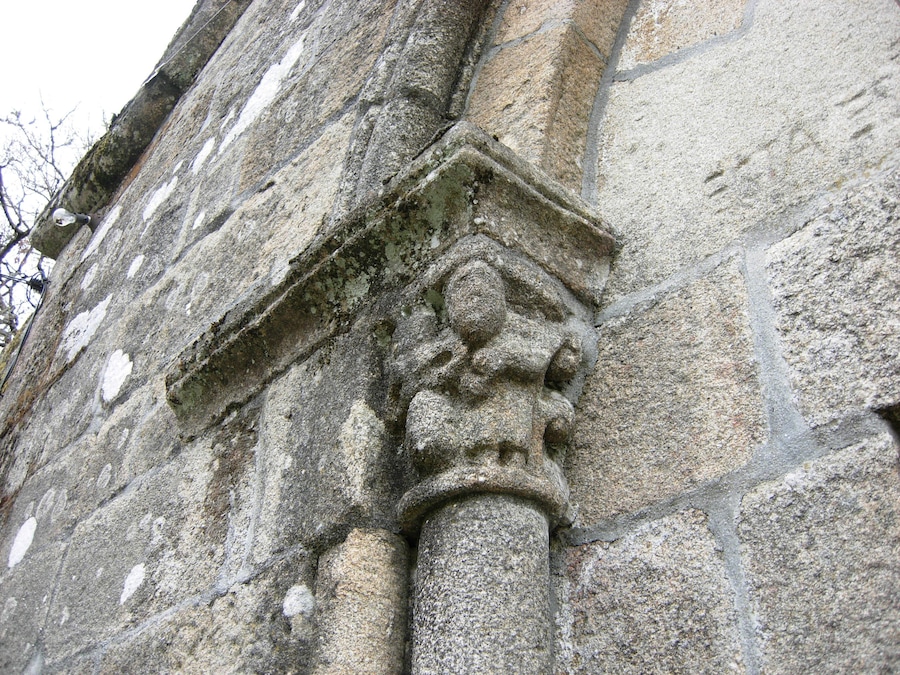 A stone building with a carved column and a triangular pediment.