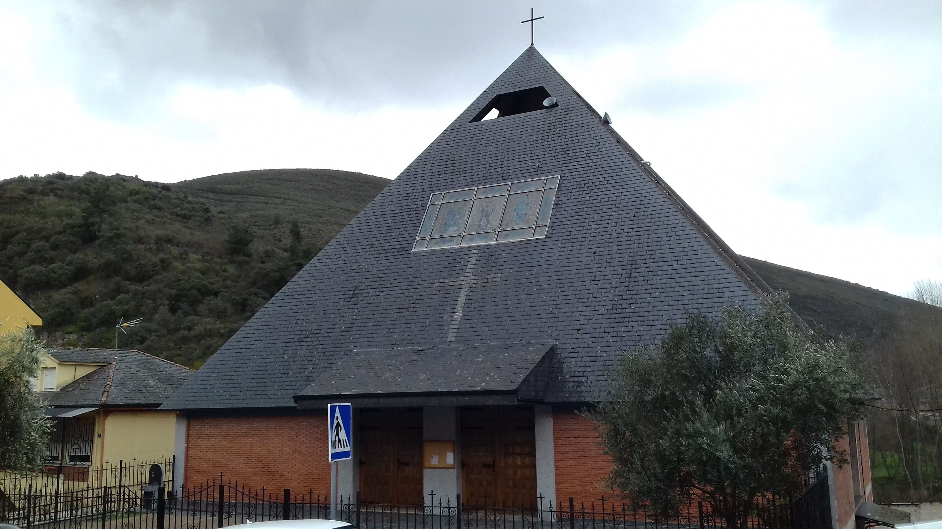 A church with a steep, dark roof and a cross on top.