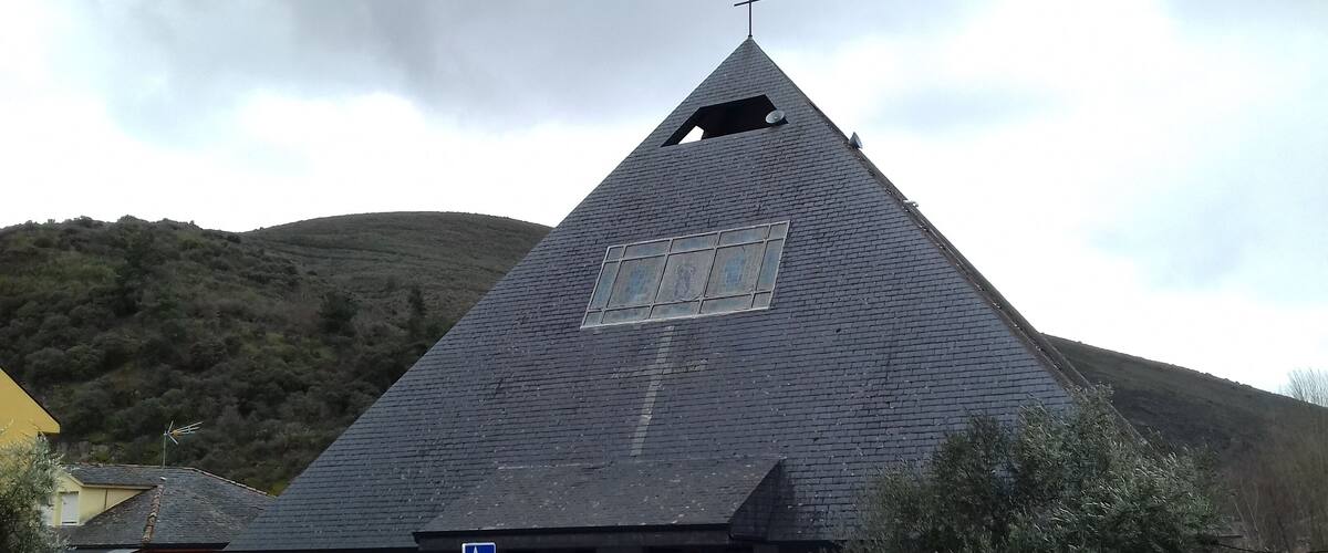 A church with a steep, dark roof and a cross on top.