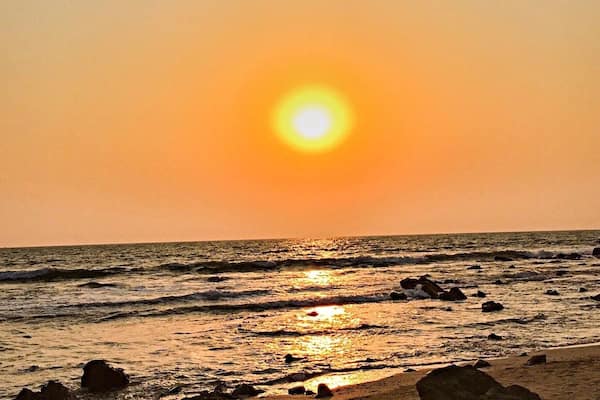 A sunset over a rocky beach with waves.