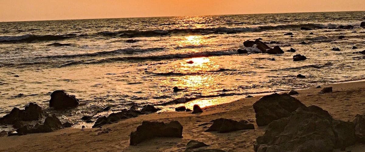 A sunset over a rocky beach with waves.