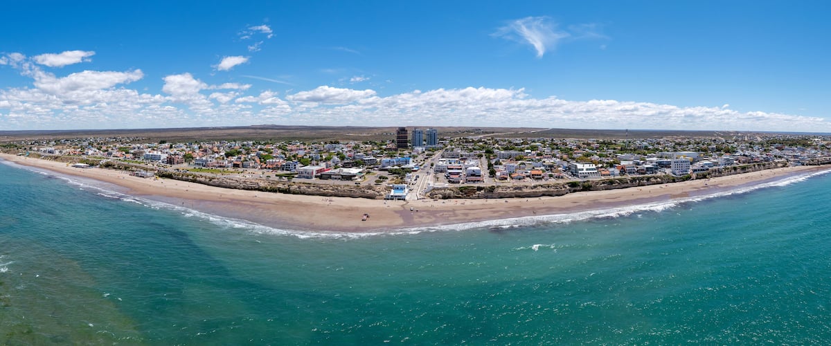 A coastal city with a beach, buildings, and a clear sky.
