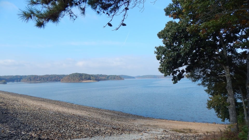 A rocky shoreline with a calm lake and distant islands.