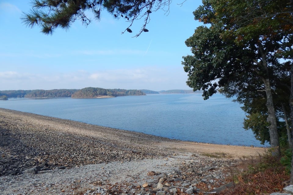 A rocky shoreline with a calm lake and distant islands.