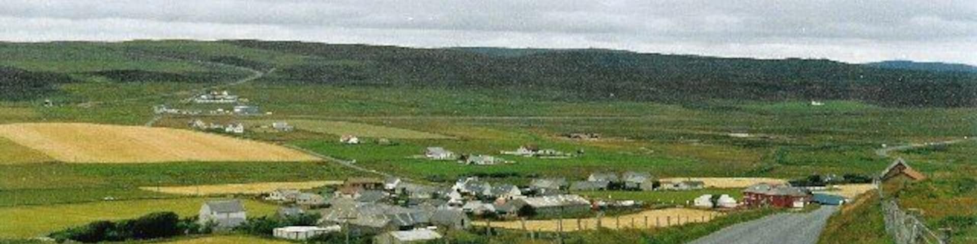 Veensgarth and Tingwall airport. Viewed from the side of Herrislee Hill, looking north. The airport runway is just visible as a line stretching across the middle of the picture from the cluster of buildings in the distance.