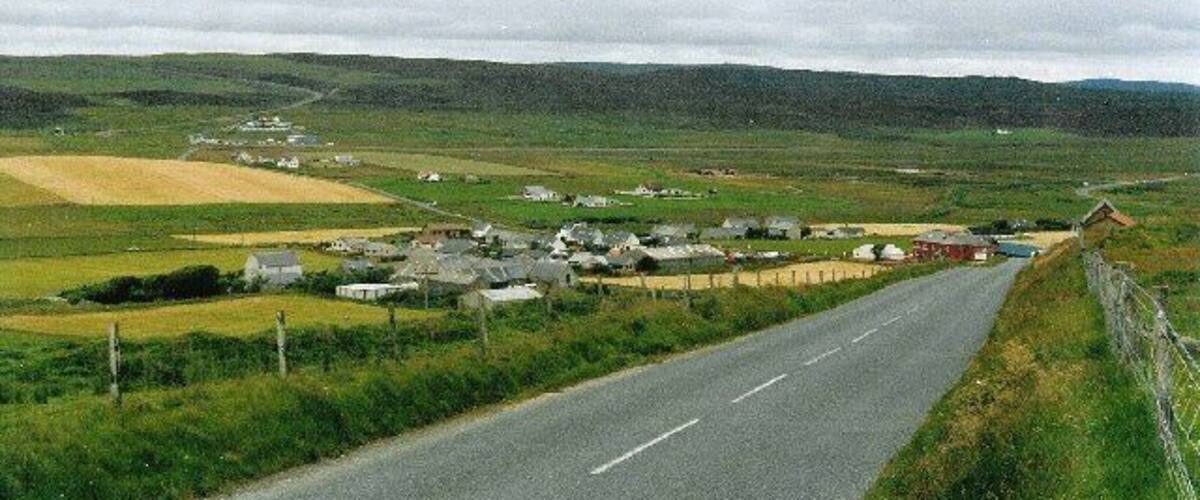 A rural road with houses and fields.