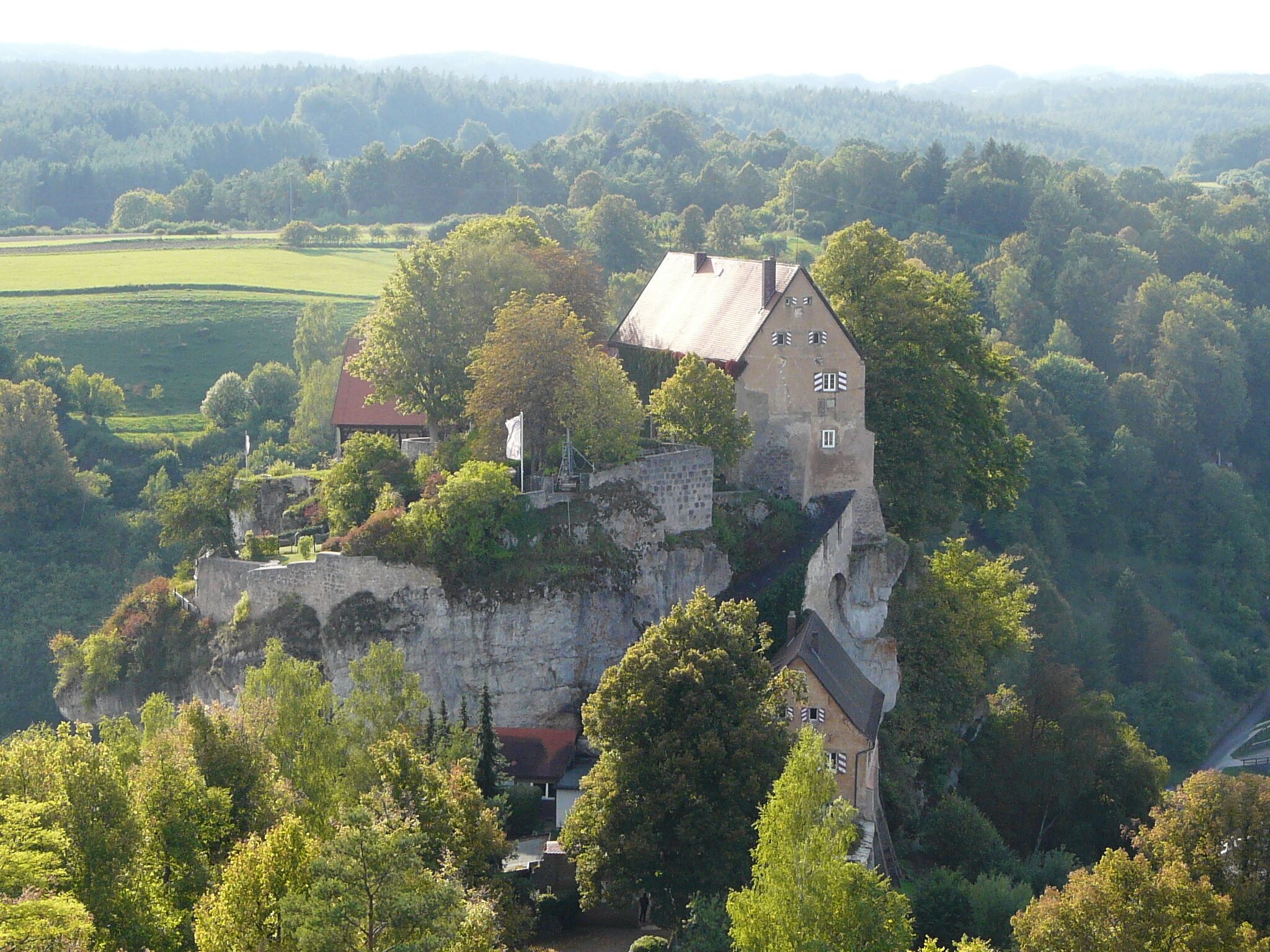 A castle perched on a cliff surrounded by lush greenery.