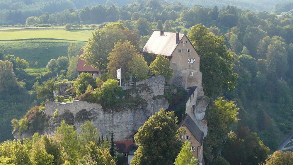 Eine Burg auf einem Felsen, umgeben von üppigem Grün.