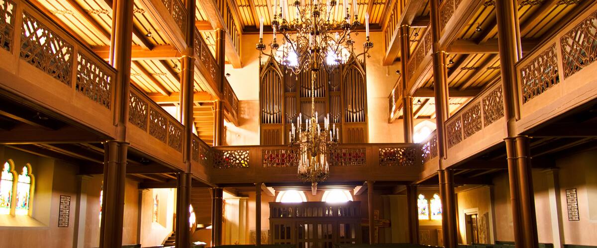 A grand hall with a large chandelier, ornate wooden ceiling, and stained glass windows.