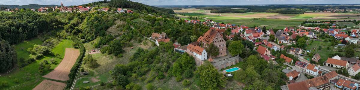 Ein Dorf mit roten Häusern, einer Kirche und einem Hügel mit Bäumen.