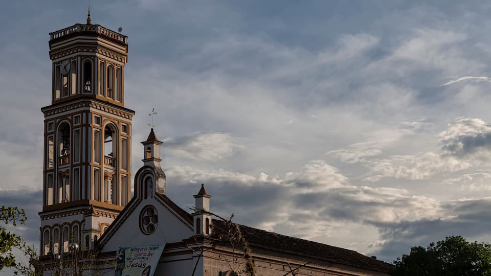 A church with a clock tower and a bell.