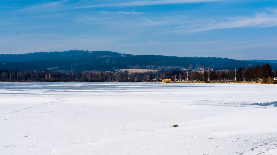 A frozen lake with a clear sky and distant hills.