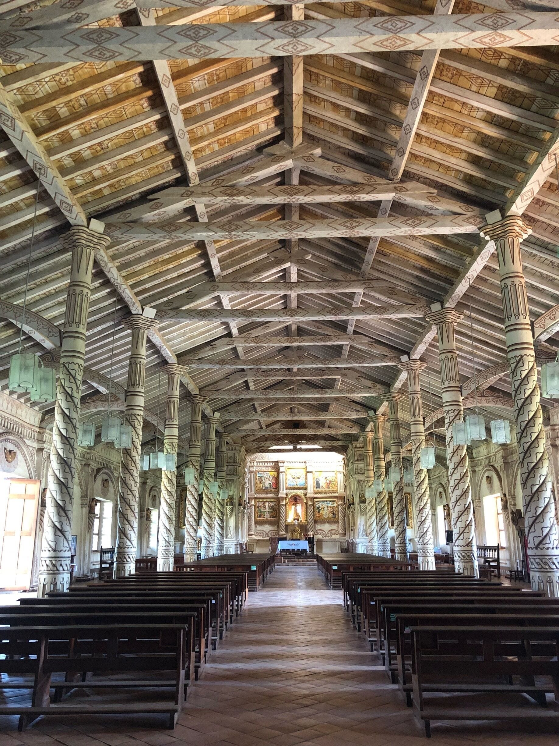 An interior of a church with a high ceiling, wooden beams, and ornate columns.