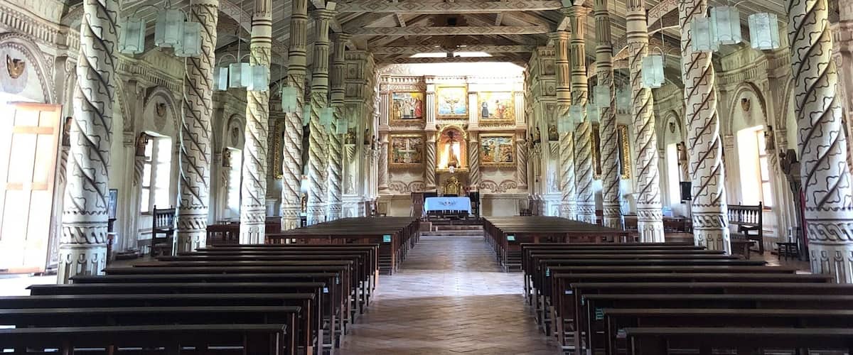 An interior of a church with a high ceiling, wooden beams, and ornate columns.