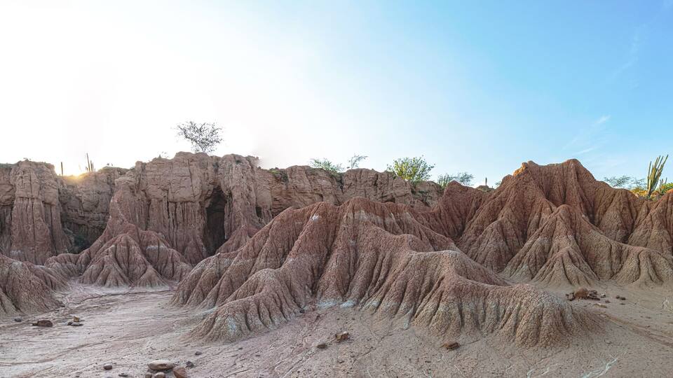 A rugged desert landscape with eroded rock formations and sparse vegetation.