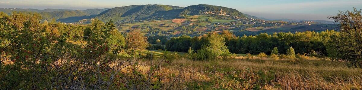 Eine gebirgige Landschaft mit blauem Himmel und einem Dorf in der Ferne.