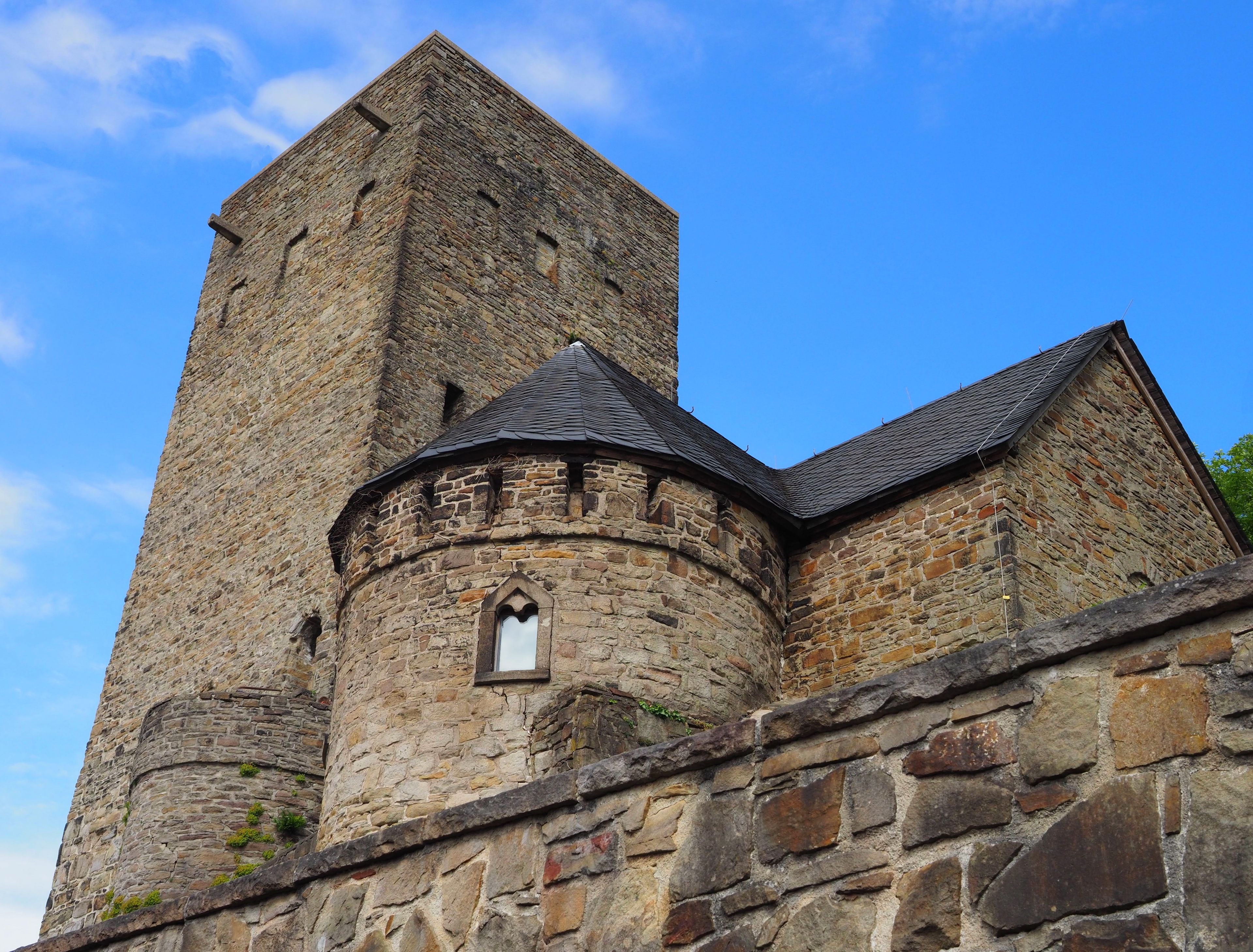 A historic stone tower with a pointed roof and a small arched window.