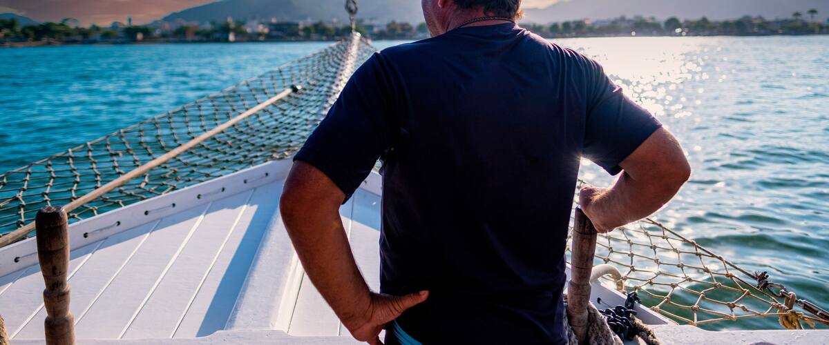 Basilian man watching the sunset on top of a schooner in the city of ubatuba praia itagua in brazil