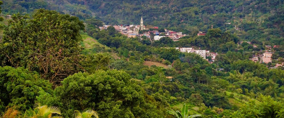 A village nestled in a valley surrounded by lush green hills.