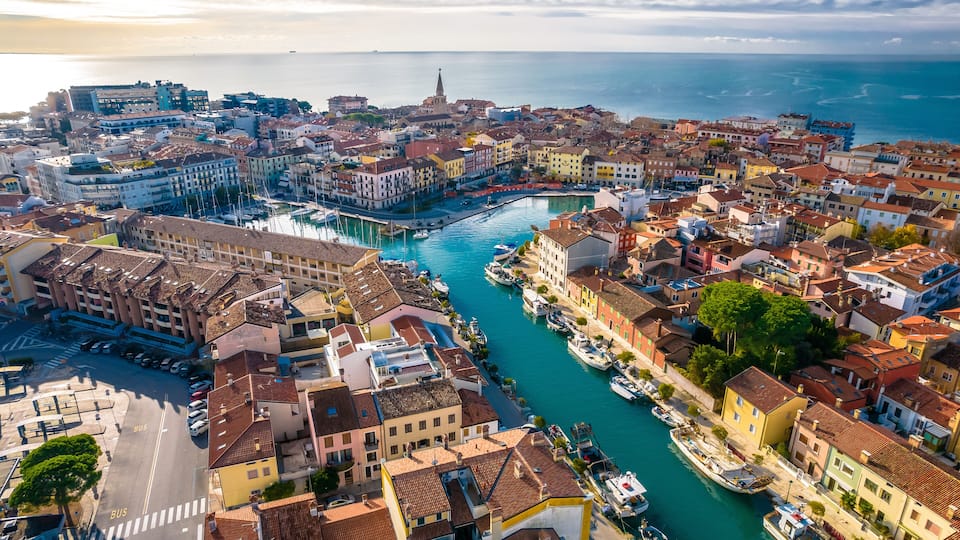 A coastal cityscape with a marina, historic buildings, and a prominent church spire.