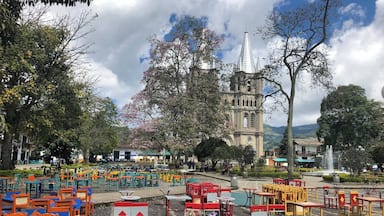 Una plaza con mobiliario exterior colorido e iglesia histórica al fondo.