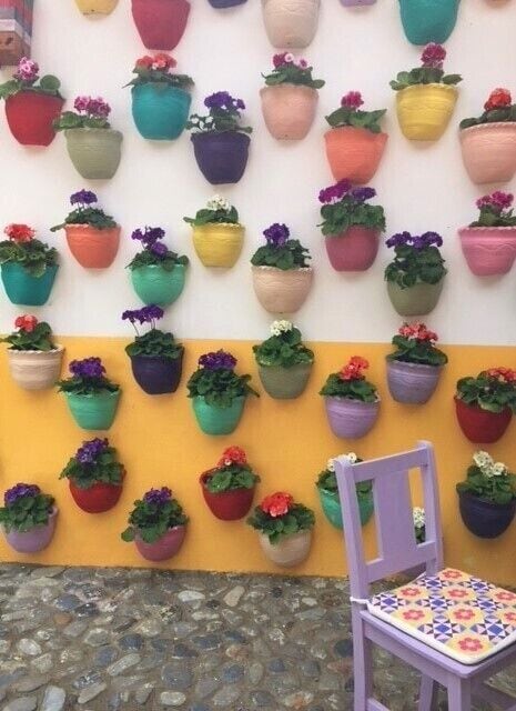 A wall with colorful hanging planters arranged in a grid pattern.