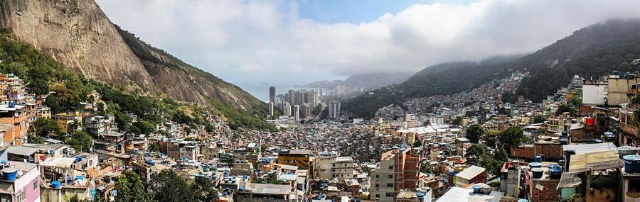 A densely populated hillside city with steep cliffs and a mix of residential and high-rise buildings.