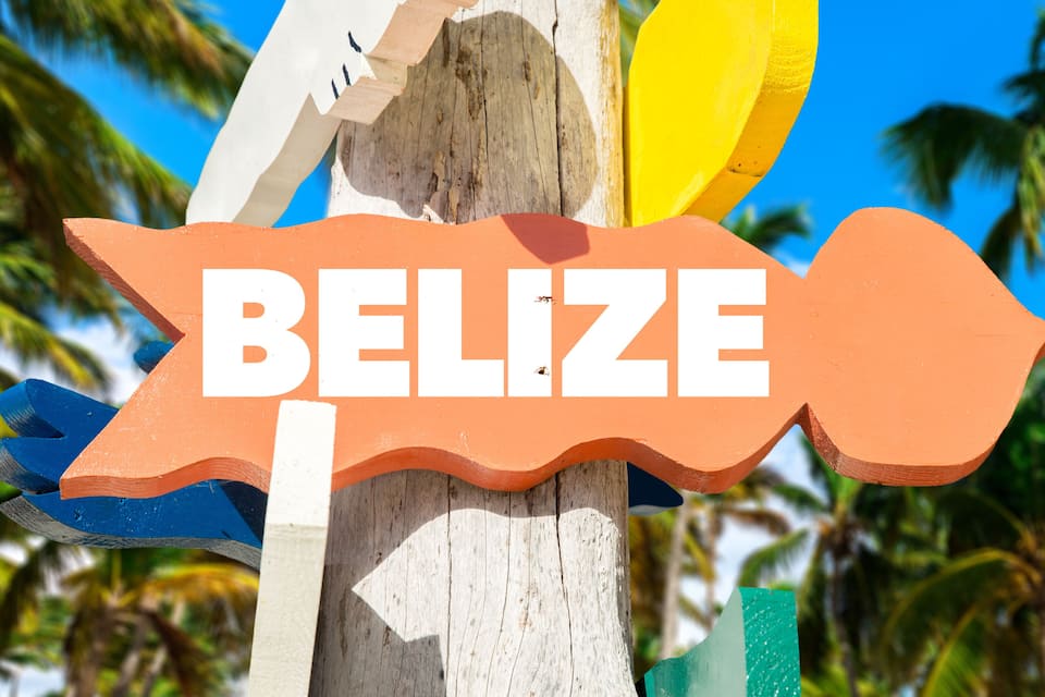 Uma placa de madeira com a palavra 'BELIZE' e uma seta apontando para a direita.