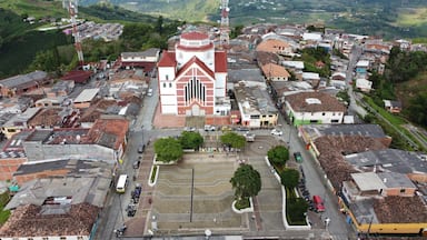 Une ville où se dresse une église remarquable, reconnaissable à sa façade rouge et blanche, et qui est entourée d’immeubles d’habitation aux toits recouverts de tuiles rouges.